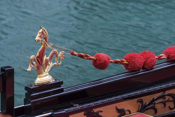 Mythological brass horse figures and red pompoms decorate the gondola, Venice, Veneto, Italy