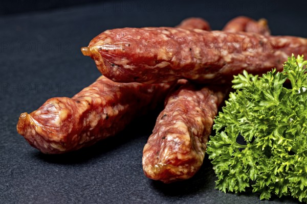 Close-up of salami with parsley on black background, crunchy pepperbite sausage