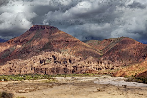 Dramatic mountain landscape with clouds and rocky areas in the foreground, the landscape and colorful rock formations of the Quebrada de Cafayate near Salta in Argentina