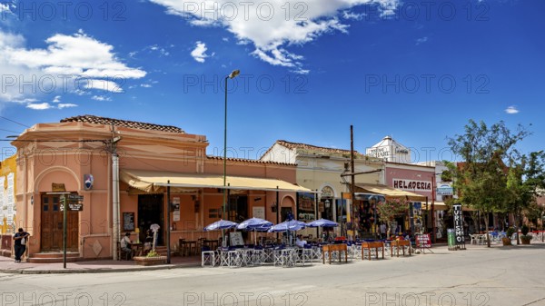 Urban street scene with restaurants and outdoor seating under a clear blue sky, Downtown Cafayate, Argentina