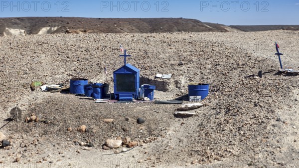 A blue grave with crosses in a barren desert landscape under a clear sky, grave in the Quebrada de Cafayate near Salta in Argentina