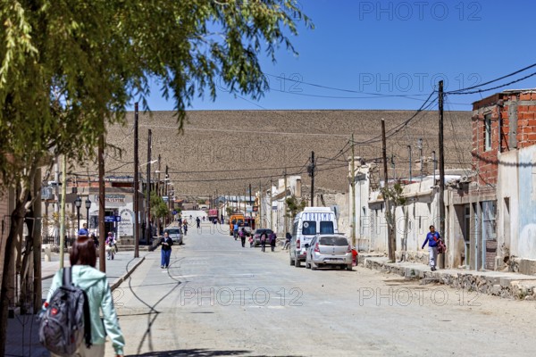 Busy street in a small village surrounded by dusty hills under bright sunshine, San Antonio de los Cobres, Salta Province, Argentina