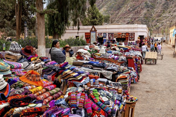 Merchants offer colorful clothes and goods at a market stand in mountainous surroundings, tourist and souvenir market of Santa Rosa de Tastil near Salta in Argentina