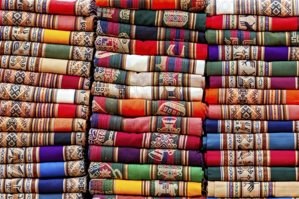 Stacked traditional cloths in bright colors and ethnic patterns, tourist and souvenir market of Santa Rosa de Tastil near Salta in Argentina
