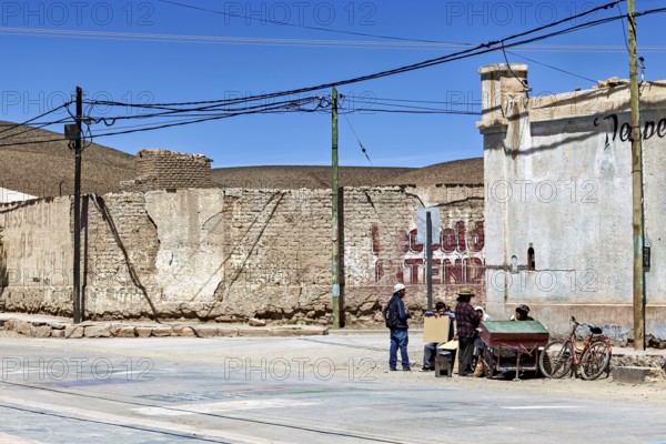 Small group of people talking on a street corner in a dry city with old buildings, San Antonio de los Cobres, Salta Province, Argentina