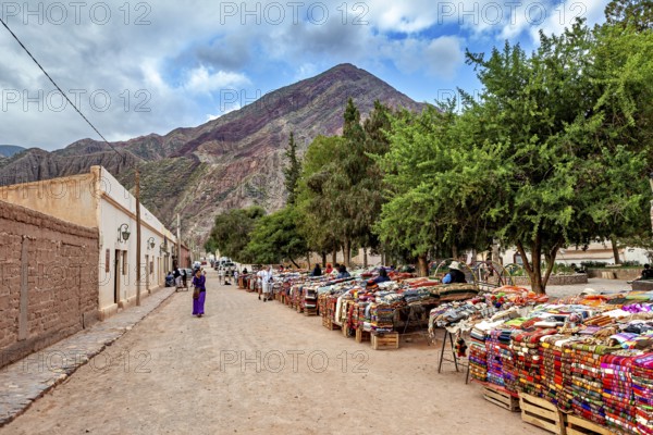 A market with colorful fabrics along a street nestled in a mountainous landscape, tourist and souvenir market of Santa Rosa de Tastil near Salta in Argentina