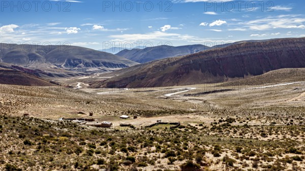Wide plain with few shrubs, surrounded by barren desert and mountains, the landscape and colorful rock formations of the Quebrada de Cafayate near Salta in Argentina