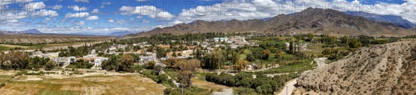 Panorama of a green village nestled in hilly and mountainous landscape, roads through the Quebrada de Cafayate countryside near Salta in Argentina