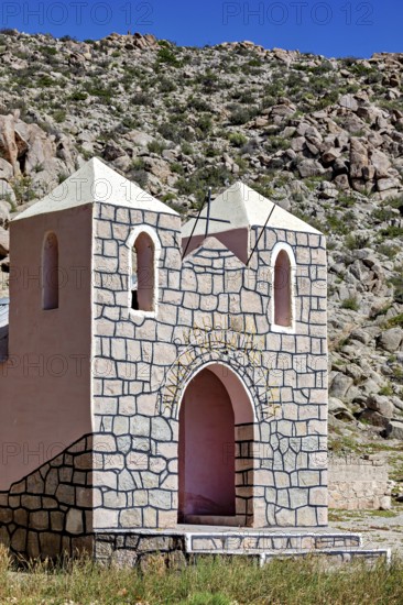 Small stone chapel in a remote desert landscape against a rocky backdrop under a blue sky, The chapel in Santa Rosa de Tastil near Salta in Argentina