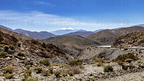 Winding road through a mountainous and dry landscape under blue sky, roads through the Quebrada de Cafayate countryside near Salta in Argentina