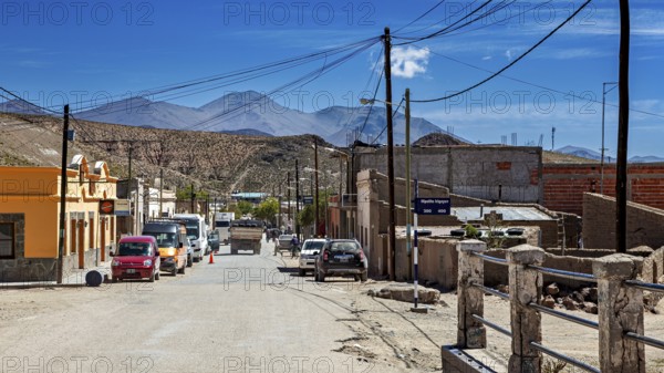 Several cars in a hilly desert town surrounded by mountains under blue skies, San Antonio de los Cobres, Salta Province, Argentina