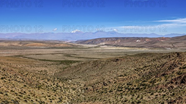 Wide desert landscape under clear blue sky with distant mountains, roads through the Quebrada de Cafayate countryside near Salta in Argentina