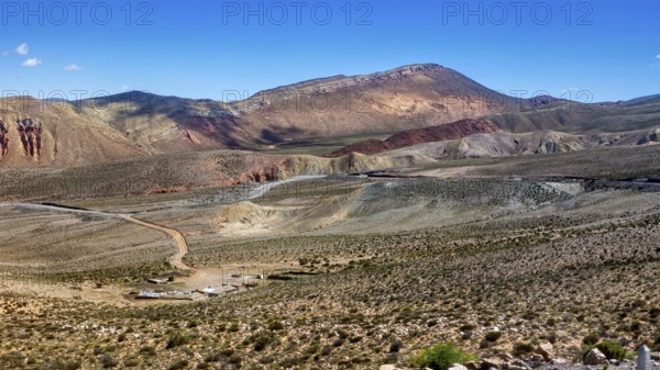 View of barren desert landscape with hills and mountains under clear skies, roads through the Quebrada de Cafayate countryside near Salta in Argentina