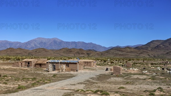 Cabins in an open desert landscape with dry soil and mountains in the background, San Antonio de los Cobres, Salta Province, Argentina
