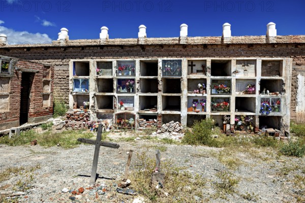Weathered wall with grave niches and cross in an old cemetery, The cemetery of Cachi in Argentina