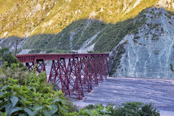 Red bridge over a dry riverbed in a mountainous landscape, roads through the Quebrada de Cafayate countryside near Salta in Argentina