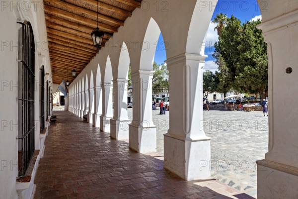 Long arcade with wooden ceiling, combines interior with a sunny square, The arcades of Cachi in Argentina