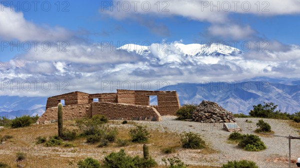 Old stone ruin in a desert-like landscape with mountains in the background and snow-capped peaks, ruins with the snow-capped peaks of the Andes in the background in Argentina near Salta