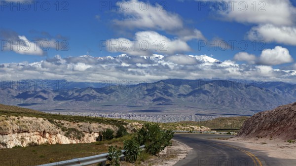 Curvy road leads through a vast landscape with mountains and clouds in the sky, roads through the landscape of Quebrada de Cafayate near Salta in Argentina
