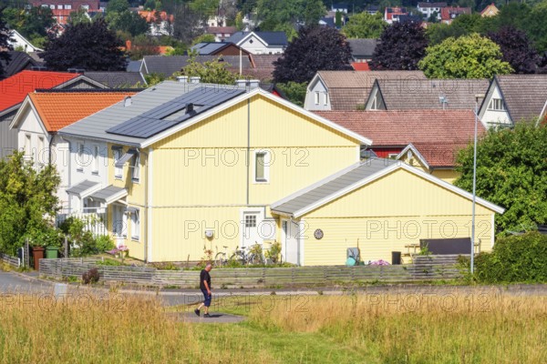 Alone man walking on a walkway in a residential area with wooden houses a sunny summer day, Falköping, Sweden