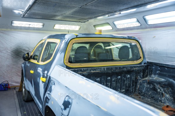 Truck body masked and prepped inside a professional automotive paint booth, showing meticulous restoration work and precision preparation for primer and final finish