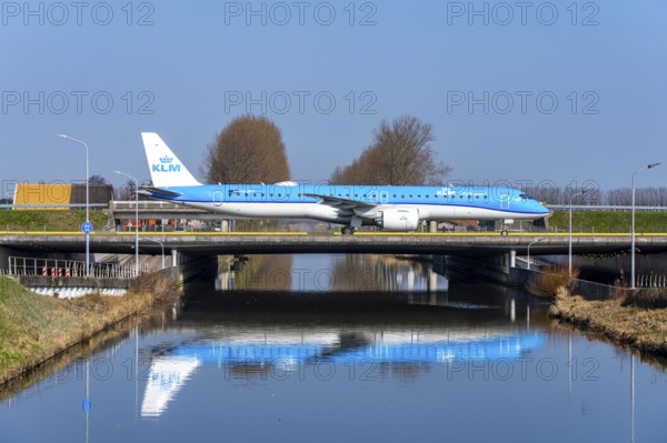 Taxiway bridge over a canal near Hoofddorp, on the Polderbaan, a runway in the west of Amsterdam Schiphol Airport, KLM Embraer E195-E2, aircraft rolls to the terminal after landing, Netherlands