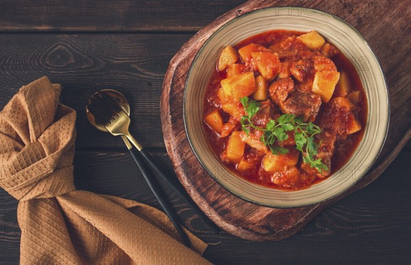 Stew with potatoes, in tomato sauce, with spices and herbs, close-up, no people, on a black background