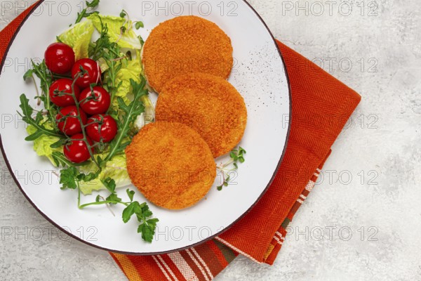Crispy fried fish cutlets, fish burgers, on a white plate, with fresh lettuce leaves, arugula and cherry tomatoes, homemade, no people