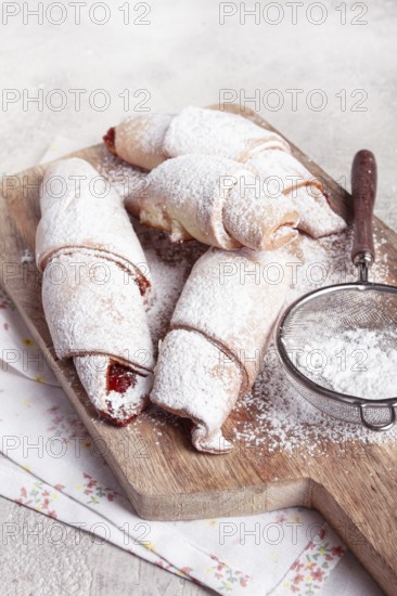 Bagels with filling, sweet pastries, sprinkled with powdered sugar, on a wooden board, dessert, breakfast