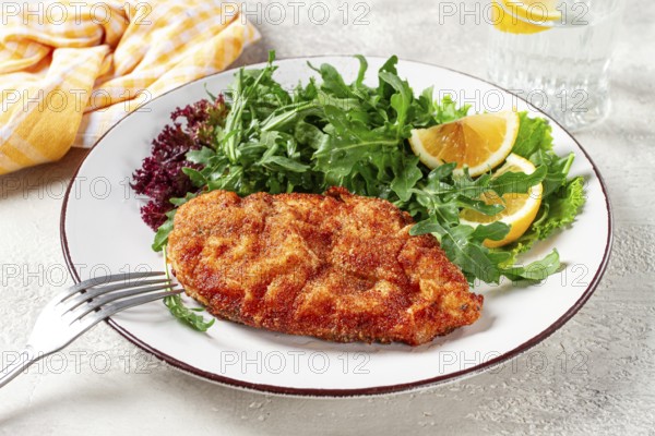 Milanese chicken, Crispy breaded chicken served, with fresh herbs, and lemon wedges