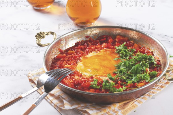 Traditional Turkish dish, scrambled eggs with tomatoes, Menemen, with herbs, in a frying pan, close-up, no people