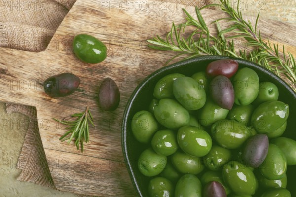 Chalkidiki olives, classic Greek green olives, in a bowl on a cutting board, top view, without people