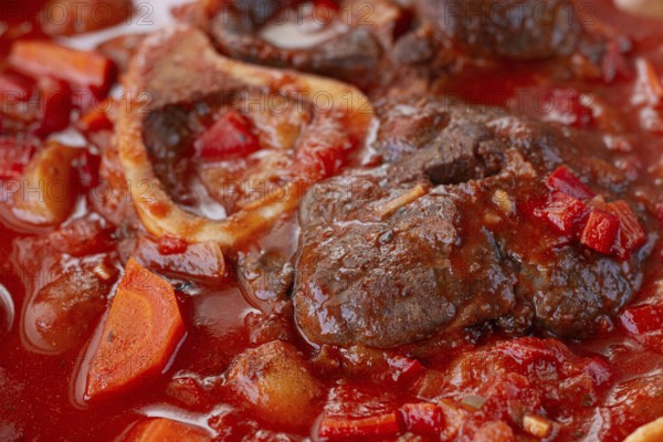 Ossobuco stew with vegetables, knuckle on the bone with new potatoes, in tomato sauce, homemade, top view, no people