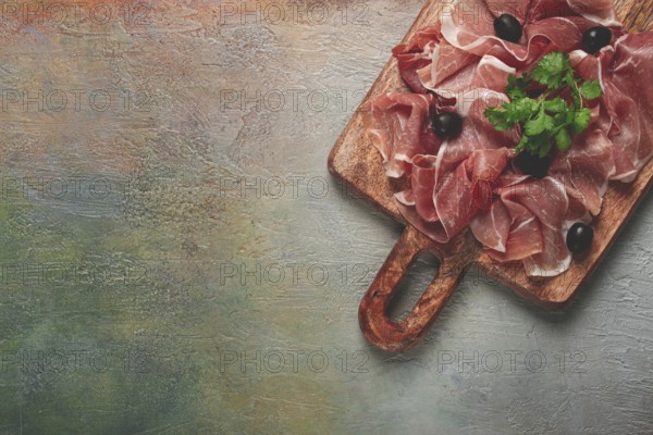 Sliced prosciutto, on a cutting board, with olives and herbs, snack, breakfast, no people