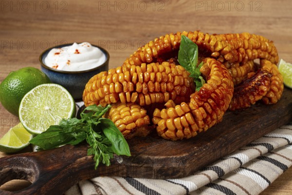 Corn ribs, with cream sauce, spices and lime, appetizer, on a wooden cutting board, homemade, no people