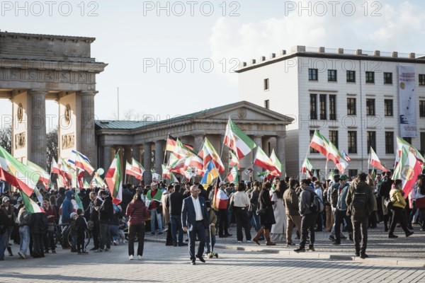 Participants carry Iranian flags from the Pahlavi period and the historic Persian flag during the demonstration by exiled Iranians under the motto Freedom for Iran led by Prince Reza Pahlavi in Berlin, Brandenburg Gate on 01.03.2026. The reason for the meeting is the joint attack by Iran by Israel and the USA and the resulting death of the previous leader Ali Khamenei