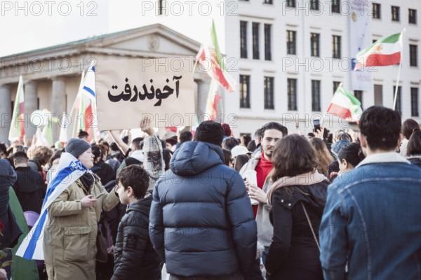 A person holds up a sign with the inscription The Mullah Went during the demonstration by exiled Iranians under the slogan Freedom for Iran led by Prince Reza Pahlavi in Berlin, Brandenburg Gate on 01.03.2026. The reason for the meeting is the joint attack by Iran by Israel and the USA and the resulting death of the previous leader Ali Khamenei