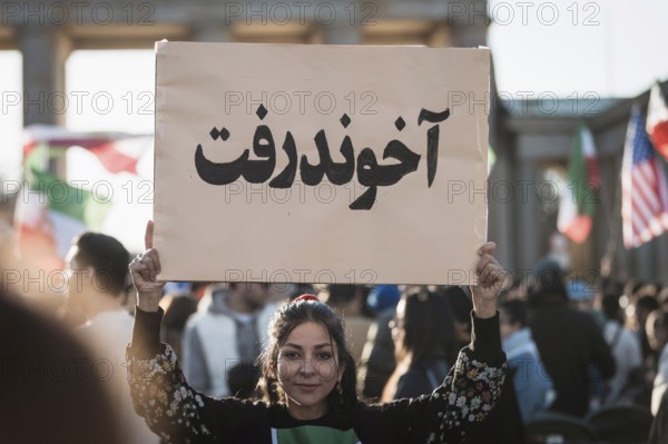 A woman holds up a sign with the inscription The Mullah Went during the demonstration by exiled Iranians under the slogan Freedom for Iran led by Prince Reza Pahlavi in Berlin, Brandenburg Gate on 01.03.2026. The reason for the meeting is the joint attack by Iran by Israel and the USA and the resulting death of the previous leader Ali Khamenei