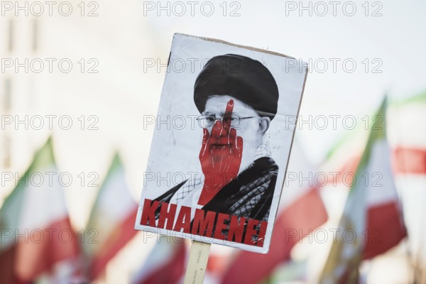 Sign for Khmenei with red middle finger at the demonstration by exiled Iranians under the slogan Freedom for Iran led by Prince Reza Pahlavi in Berlin, Brandenburg Gate on 01.03.2026. The reason for the meeting is the joint attack by Iran by Israel and the USA and the resulting death of the previous leader Ali Khamenei