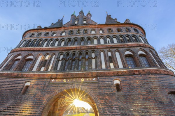 15th century Brick Gothic city gate Holstentor, Holstein Gate in the Hanseatic town Lübeck at sunset in winter, spring, Schleswig-Holstein, Germany