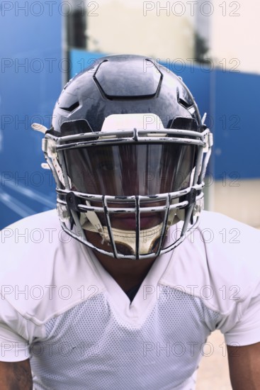 An American football player dressed in full uniform and helmet, ready for action. The scene captures the intensity and spirit of the sport, focusing on the player's determination