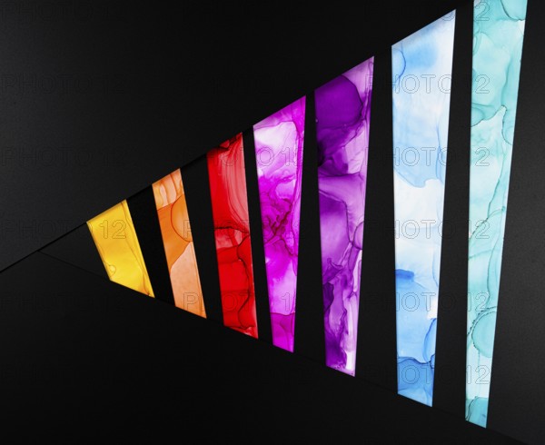 A vibrant geometric pattern with colorful segments on a black background of paper. Each segment features bright hues such as yellow, red, pink, and blue, offering a striking contrast