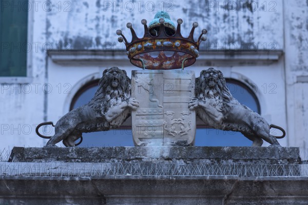 Two lion sculptures with a coat of arms and crown in front of a palazzo, Venice, Veneto, Italy