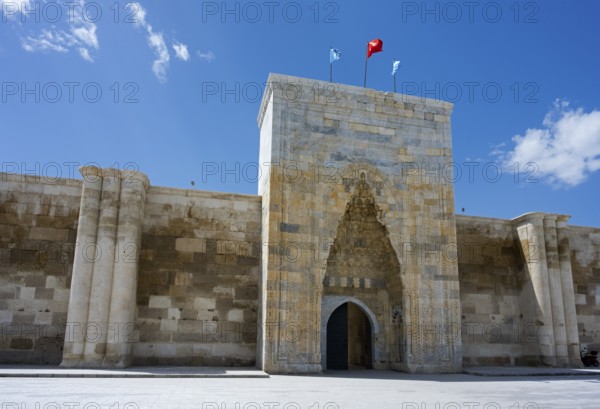 Historic fortress entrance with two flags under a cloudless sky, portal of the Sultanhani caravanserai, on the former Silk Road, museum, Sultanhani Kervansaray, Sultanhani, Aksaray province, Turkey