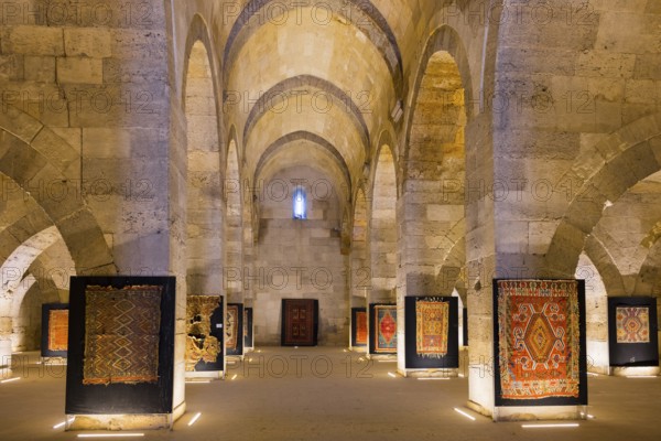 Large stone hall with illuminated carpets between imposing arches, Sultanhani caravanserai, on the former Silk Road, museum, Sultanhani Kervansaray, Sultanhani, Aksaray province, Turkey
