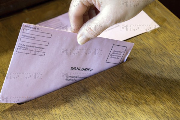 Absentee voting symbol: A ballot letter is thrown into the ballot box of a municipal administration