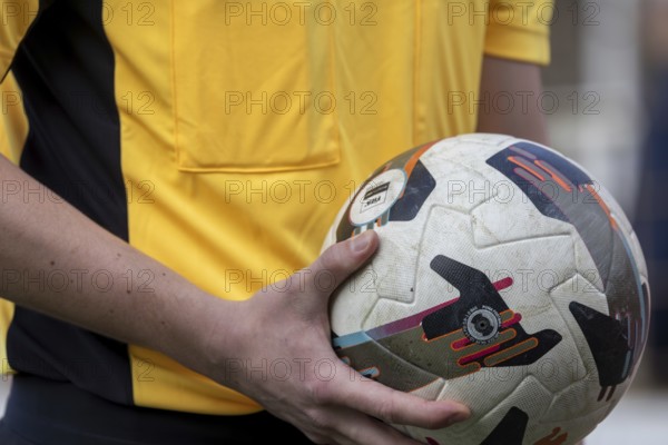 Close-up of a referee holding a ball just in front of the start of a soccer game