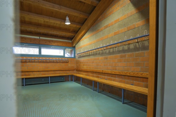 A changing room with long wooden benches and brick walls, hooks for clothes, blue light, Schlehengäu Grund Schule Gechingen, Calw district, Germany
