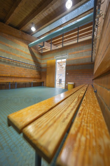 A light-flooded changing room with wooden benches and brick walls, turquoise floor, Schlehengäu Grund Schule Gechingen, Calw district, Germany