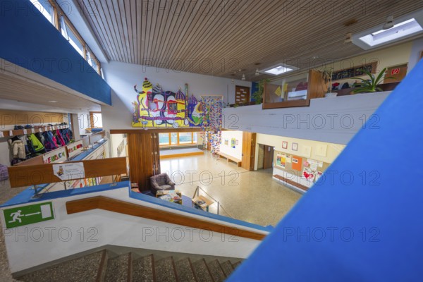 An interior with a staircase, decorated with art and a pleasantly illuminated wooden ceiling, Schlehengäu Grund Schule Gechingen, Calw district, Germany